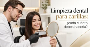 Limpieza dental para carillas: odontólogo revisa el color con guía de tonos y paciente sonríe frente al espejo